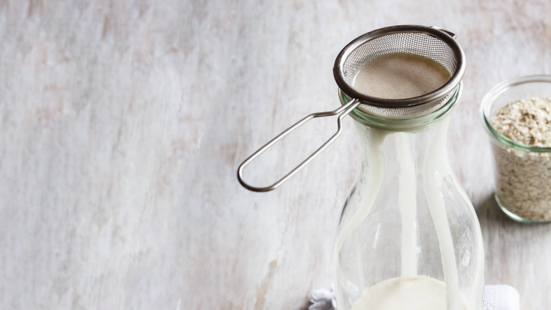 Mit Haferflocken, einer Flasche, einem Sieb und Wasser wird Hafermilch gemacht. Mit Haferflocken, einer Flasche, einem Sieb und Wasser wird Hafermilch gemacht.
