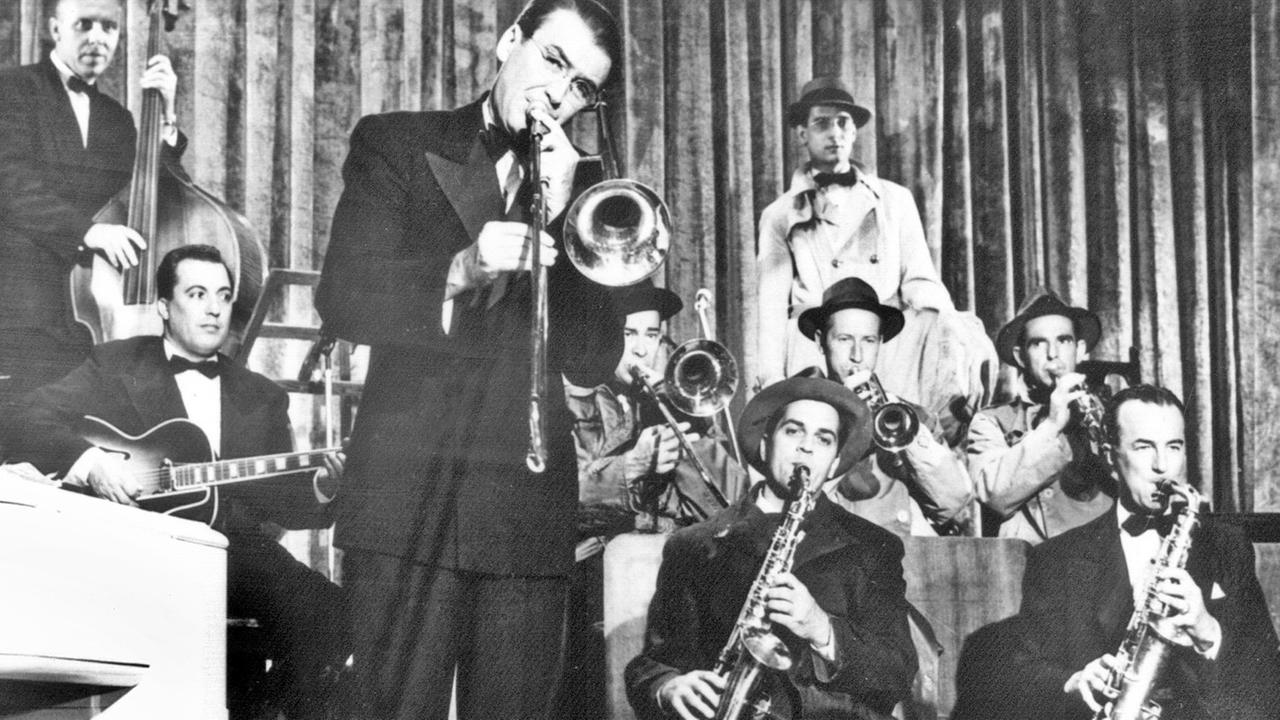 Glenn Millers weltbekannte Band, die in den späten Dreißiger und den frühen Vierziger Jahren Amerikas Spitzentanzorchester war – hier in einer Szene des biografischen Filmes "Die Glenn Miller Story" mit James Stewart (Mitte, mit Posaune) als Glenn Miller. Glenn Millers weltbekannte Band, die in den späten Dreißiger und den frühen Vierziger Jahren Amerikas Spitzentanzorchester war – hier in einer Szene des biografischen Filmes "Die Glenn Miller Story" mit James Stewart (Mitte, mit Posaune) als Glenn Miller.