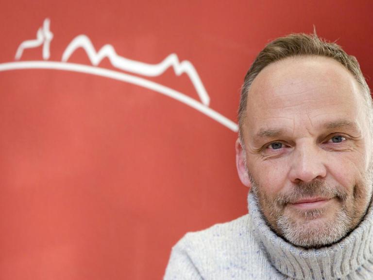 Porträt vom Bürgermeister Dirk Neugebauer vor einem roten Hintergrund.