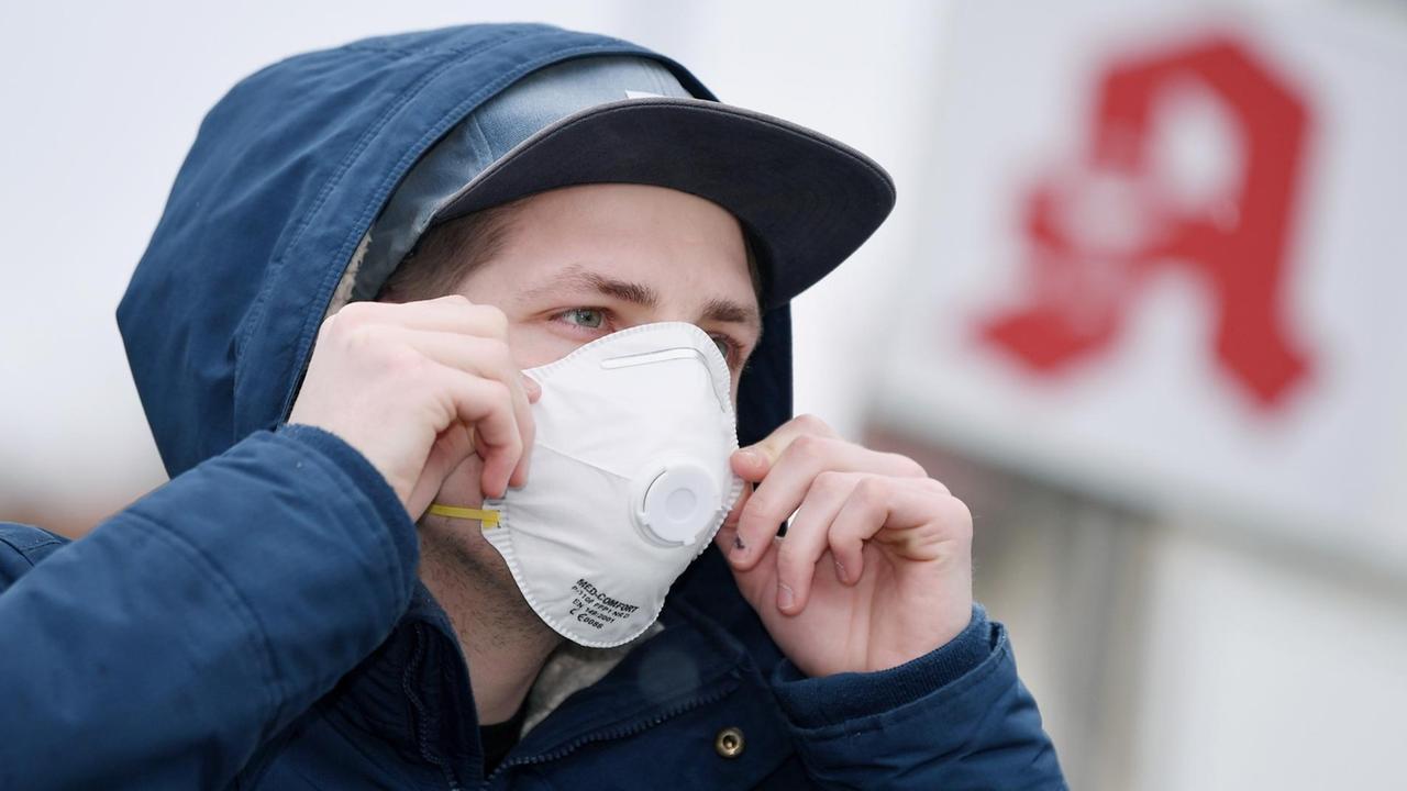 Ein Mann mit einer Schutzmaske vor einer Apotheke, Schutzmasken sind fast ausverkauft. Ein Mann mit einer Schutzmaske vor einer Apotheke, Schutzmasken sind fast ausverkauft.
