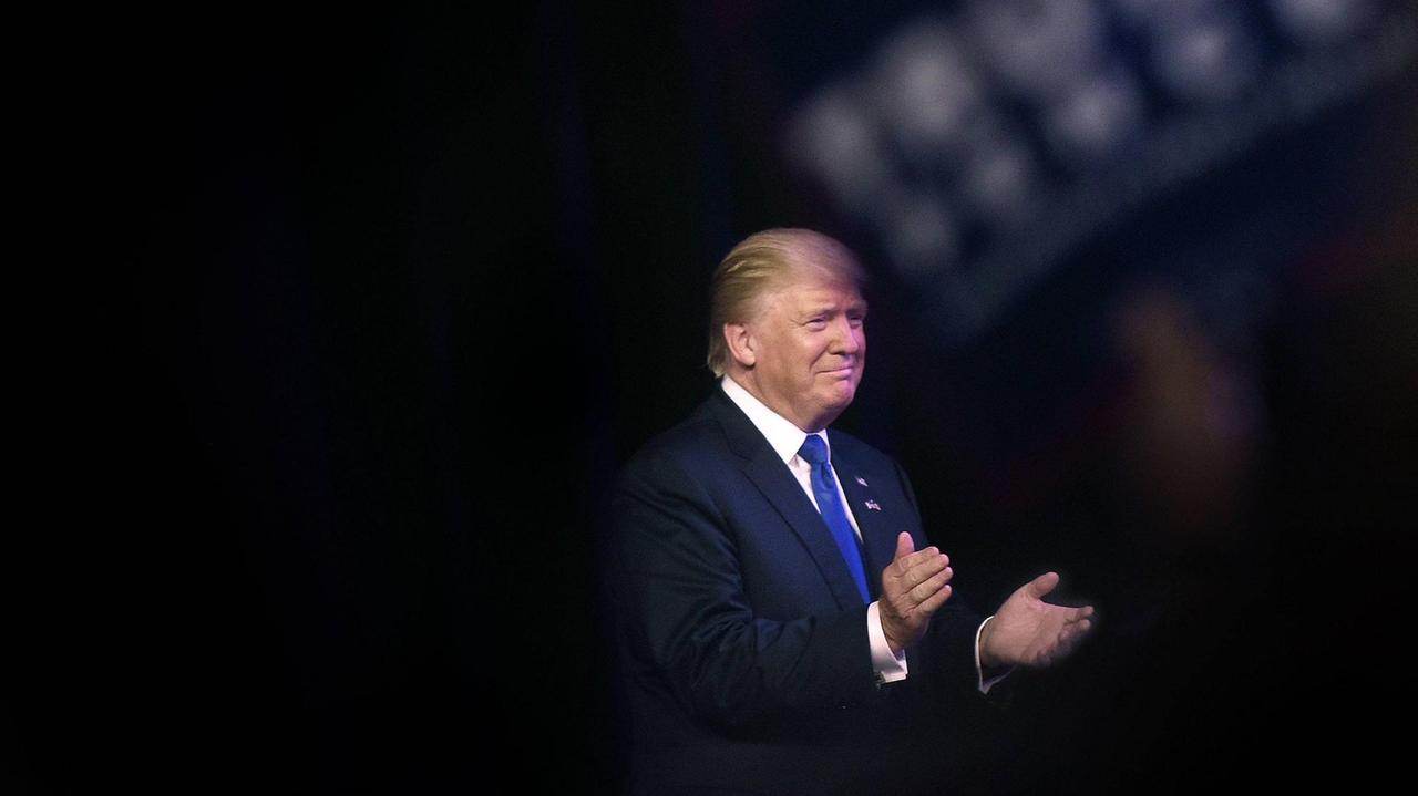 Sie sehen Donald Trump auf einer Bühne, er klatscht in die Hände. Sie sehen Donald Trump auf einer Bühne, er klatscht in die Hände.