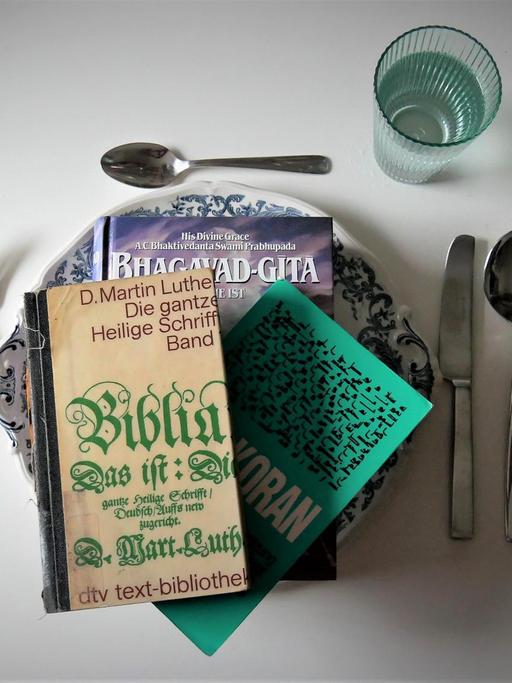 Auf einem Tisch ist ein Essgedeck angerichtet - Serviert werden religiöse Schriften