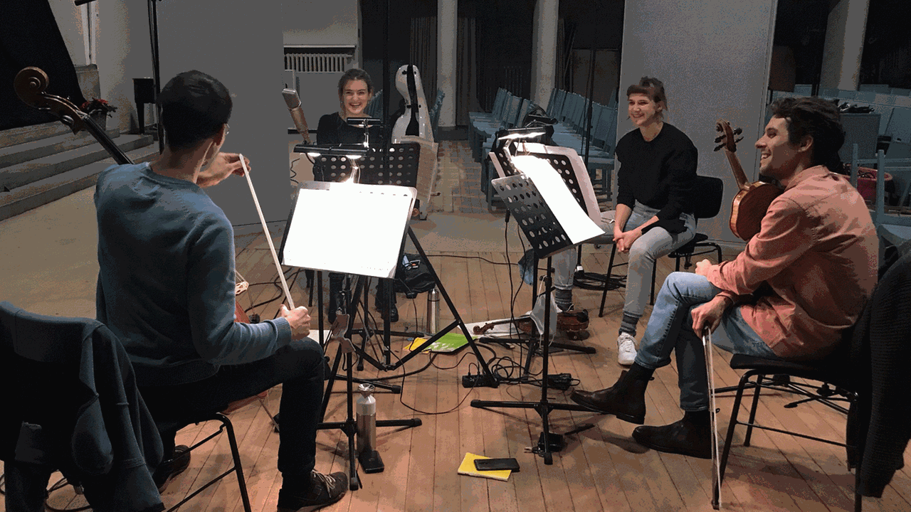 Vier Musiker sitzen mit ihren Streichinstrumenten im Kreis in einer Kirche Vier Musiker sitzen mit ihren Streichinstrumenten im Kreis in einer Kirche