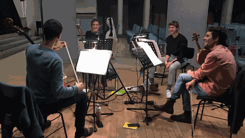 Vier Musiker sitzen mit ihren Streichinstrumenten im Kreis in einer Kirche