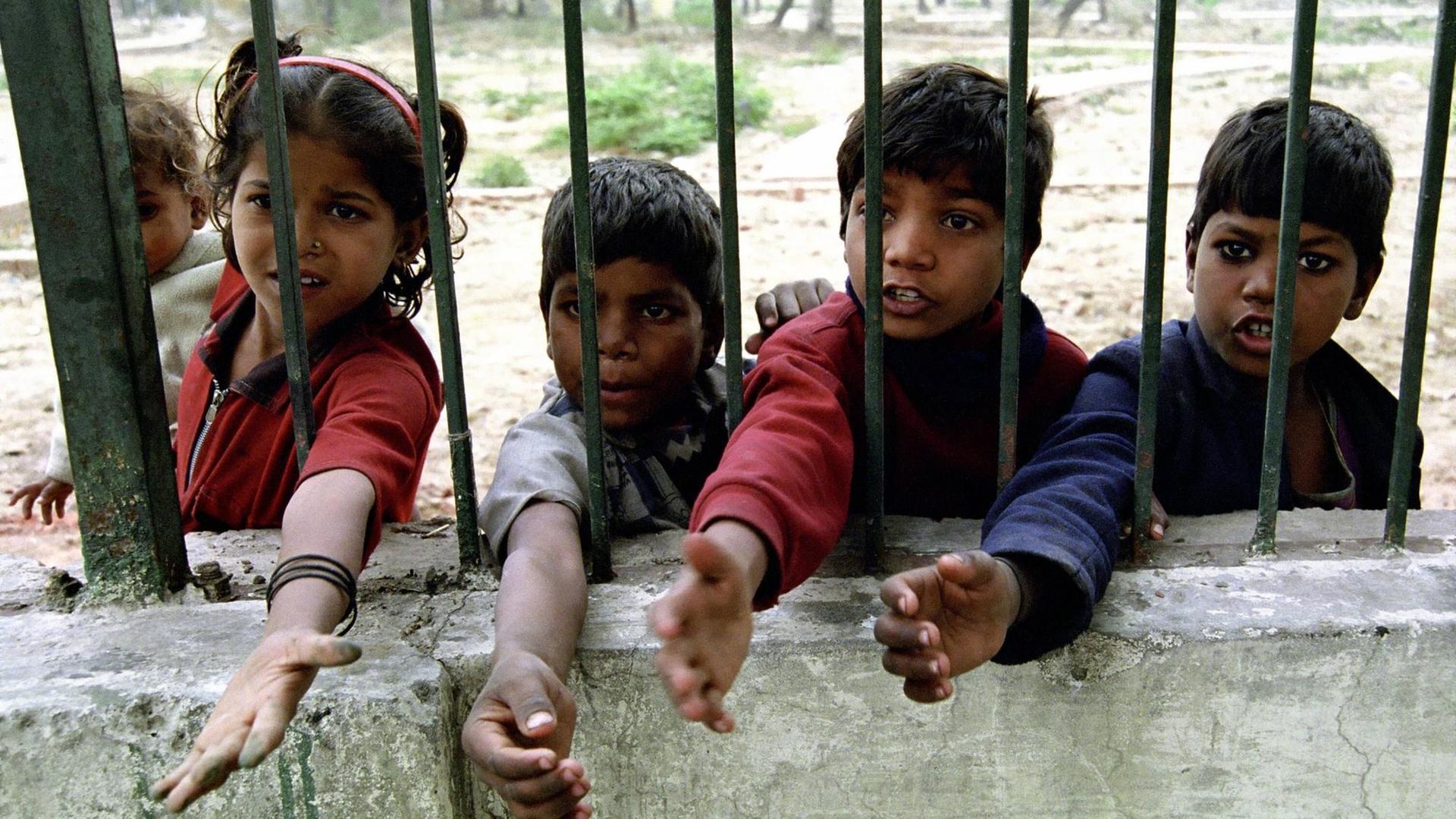 Vier Bettelnde Kinder in Neu-Delhi strecken ihre Hände durch einen Zaun (Aufnahme vom 02.02.2005)