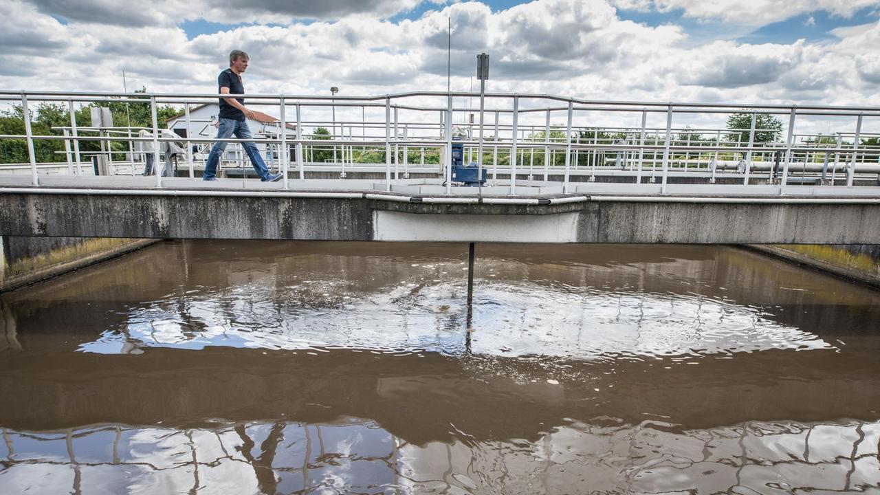 Ein Mitarbeiter der Zentralkläranlage in Büttelborn/ Hessen geht über eine Brücke, die über ein Klärbecken führt Ein Mitarbeiter der Zentralkläranlage in Büttelborn/ Hessen geht über eine Brücke, die über ein Klärbecken führt