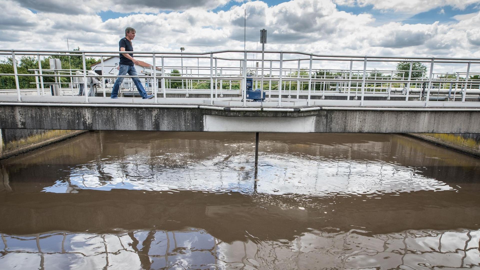 Ein Mitarbeiter der Zentralkläranlage in Büttelborn/ Hessen geht über eine Brücke, die über ein Klärbecken führt Ein Mitarbeiter der Zentralkläranlage in Büttelborn/ Hessen geht über eine Brücke, die über ein Klärbecken führt