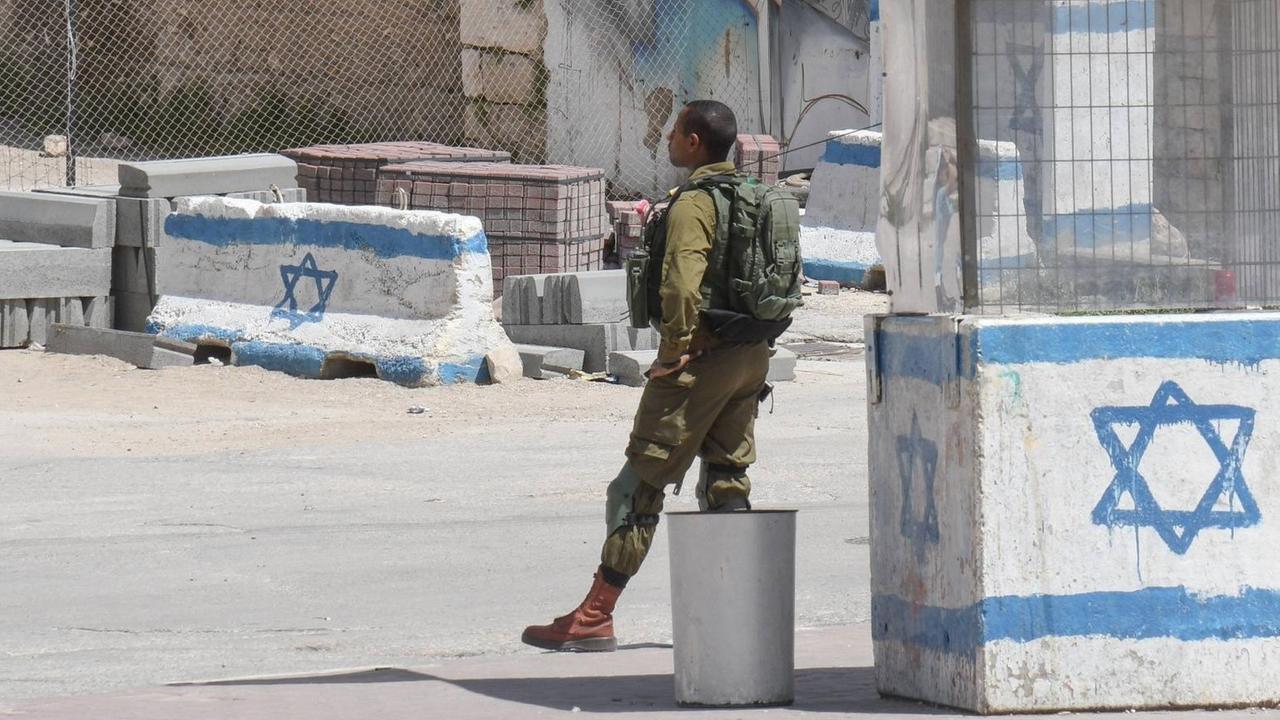 Israelische Kontrollstelle in Hebron im Westjordanland/Palaestina: Ein Israelischer Soldat in Uniform steht vor einem Wachhäuschen, das mit einer gemalten israelischen Flagge angestrichen ist. Israelische Kontrollstelle in Hebron im Westjordanland/Palaestina: Ein Israelischer Soldat in Uniform steht vor einem Wachhäuschen, das mit einer gemalten israelischen Flagge angestrichen ist.
