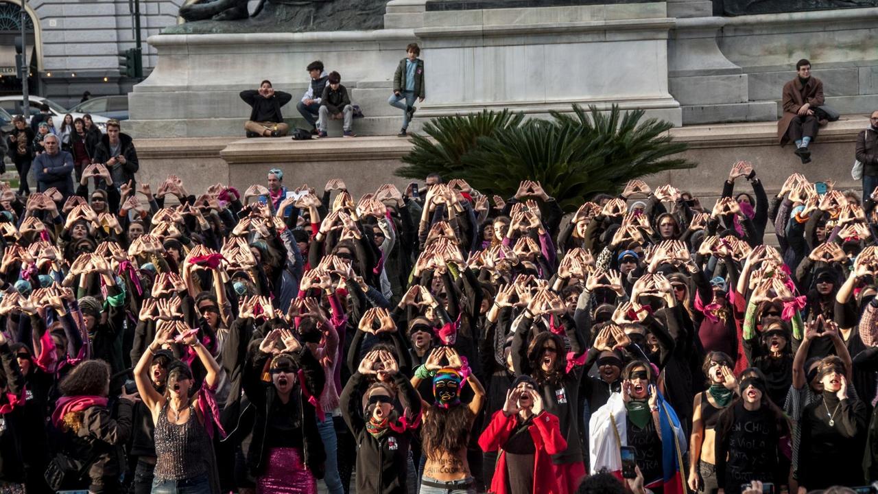 Das Bild zeigt ein Frauenkollektiv, die mit verbundenen Augen, die ausgeschreckten Hände zu einem Dreieck formen. Das Bild zeigt ein Frauenkollektiv, die mit verbundenen Augen, die ausgeschreckten Hände zu einem Dreieck formen.