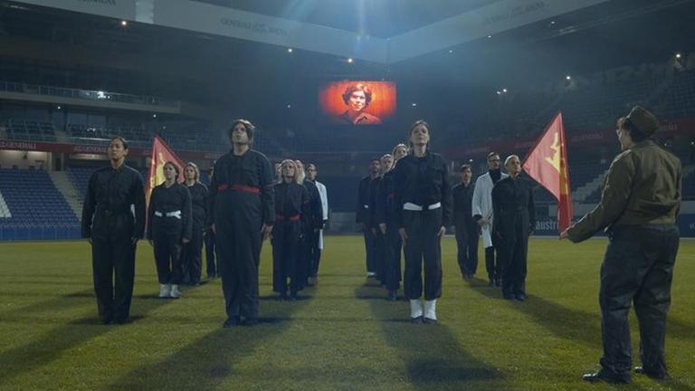 Mehrere Menschen in Uniform stehen auf einem Rasen in einem Stadion. Mehrere Menschen in Uniform stehen auf einem Rasen in einem Stadion.