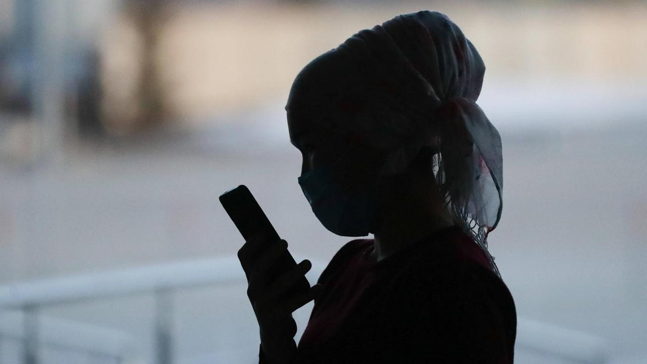 Kirgisin mit Mundschutz und Smartphone Kirgisin mit Mundschutz und Smartphone
