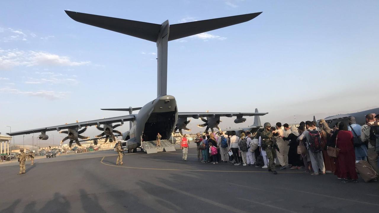 Menschen stehen Schlange, um ein deutsches Militärflugzeug zu besteigen und Kabul am Flughafen von Kabul zu verlassen. Menschen stehen Schlange, um ein deutsches Militärflugzeug zu besteigen und Kabul am Flughafen von Kabul zu verlassen.