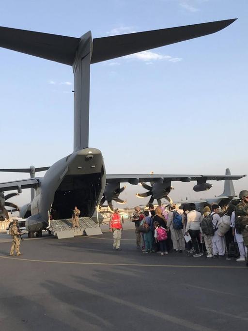 Menschen stehen Schlange, um ein deutsches Militärflugzeug zu besteigen und Kabul am Flughafen von Kabul zu verlassen.