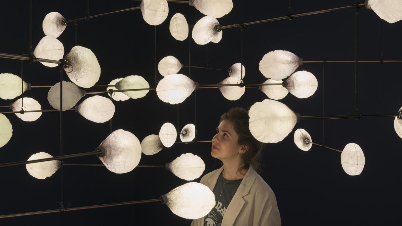 Die Installation "LeveL the Fragile Balance of Utopia", 2016, von mischer'traxler, bestehend aus weißen, lampionartigen Lichtern. Eine Museumsbesucherin besichtigt die Installation. Die Installation "LeveL the Fragile Balance of Utopia", 2016, von mischer'traxler, bestehend aus weißen, lampionartigen Lichtern. Eine Museumsbesucherin besichtigt die Installation.