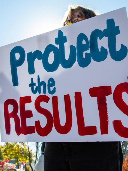 "Protect the results" steht auf einem Plakat von Demonstranten.