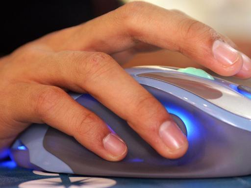 Eine Hand bedient eine Computermaus.