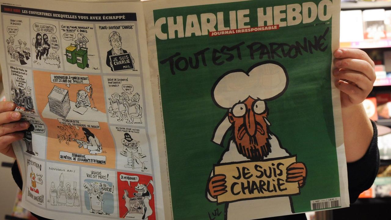 Eine Person liest in einem Pariser Kiosk die aktuelle Ausgabe der Satire-Zeitschrift "Charlie Hebdo" (14.01.2015) Eine Person liest in einem Pariser Kiosk die aktuelle Ausgabe der Satire-Zeitschrift "Charlie Hebdo" (14.01.2015)