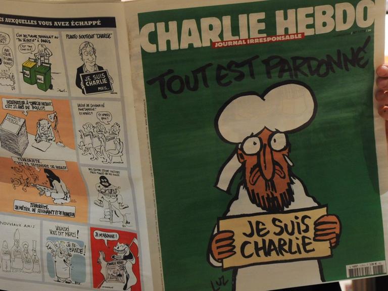 Eine Person liest in einem Pariser Kiosk die aktuelle Ausgabe der Satire-Zeitschrift "Charlie Hebdo" (14.01.2015)