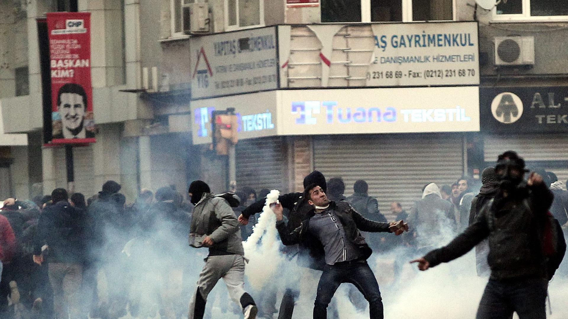 Demonstranten auf der Straße, viele laufen weg, einer wirft eine Rauchbombe. Demonstranten auf der Straße, viele laufen weg, einer wirft eine Rauchbombe.