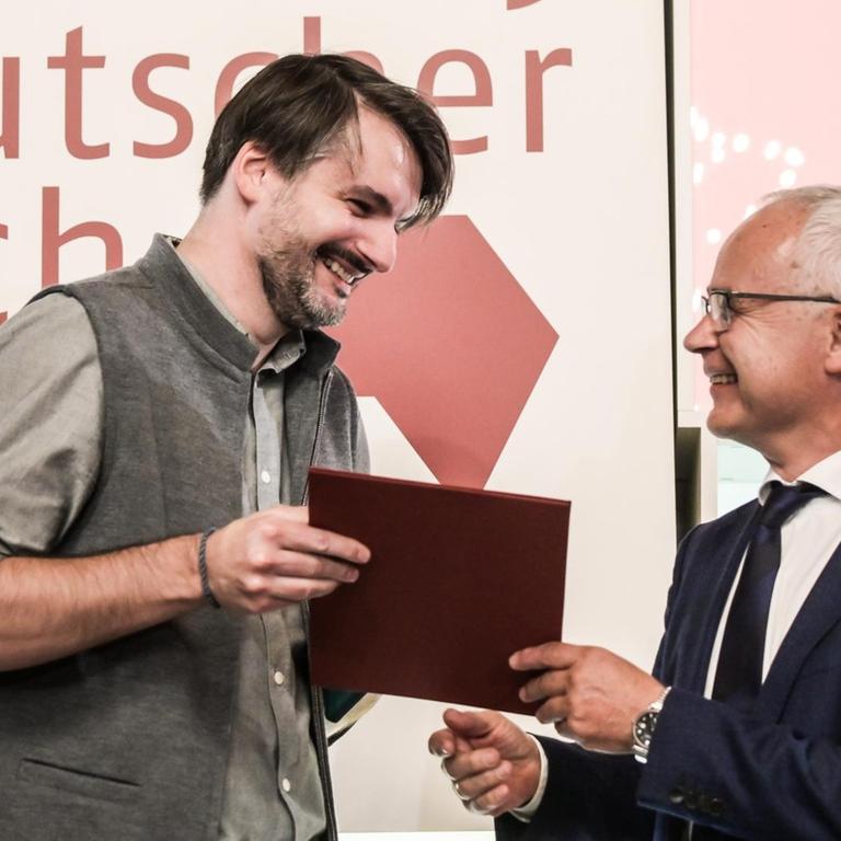 Sasa Stanisic (l) bekommt den Deutschen Buchpreis 2019 von Heinrich Riethmüller, Vorsteher des Börsenvereins des Deutschen Buchhandels. 