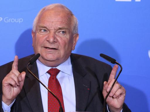 Daul spricht vor einer blauen Wand mit dem EPP-Schriftzug in zwei Mikrofone und hebt beide Zeigefiner in Schulterhöhe.