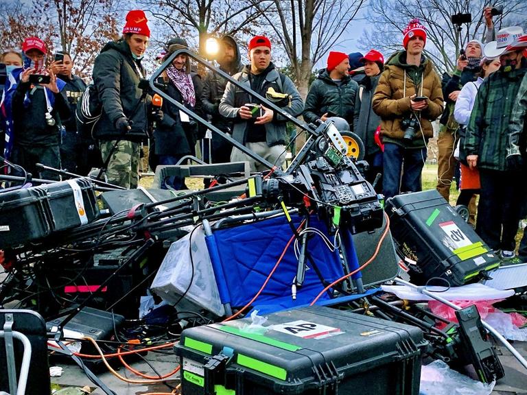 Zerstörtes Medien-Equipment liegt am 06.01.2021 vor einer Gruppe von Trump-Angängern auf dem Boden vor dem Kapitol in Washington, DC. -