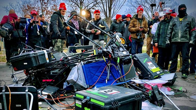 Zerstörtes Medien-Equipment liegt am 06.01.2021 vor einer Gruppe von Trump-Angängern auf dem Boden vor dem Kapitol in Washington, DC. - 