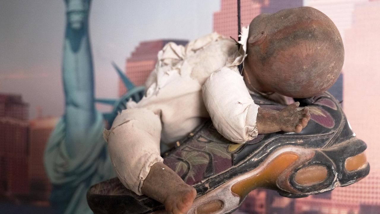 Eine kaputte Puppe liegt auf einem Turnschuh, der im Museum des Meeres von der Decke hängt. Eine kaputte Puppe liegt auf einem Turnschuh, der im Museum des Meeres von der Decke hängt.
