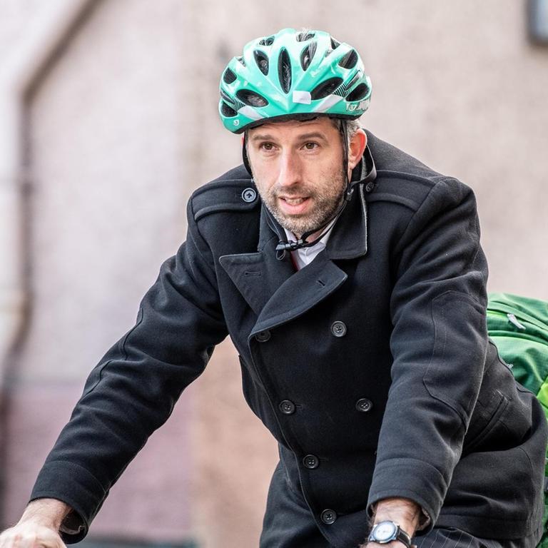 Boris Palmer, Oberbürgermeister von Tübingen (Bündnis 90/Die Grünen), kommt mit einem grünen Helm auf dem Kopf  mit dem Fahrrad zu einer Demonstration vor der Landesversorgungsanstalt der Ärzte.