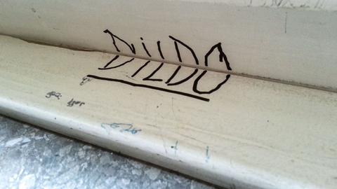 Auf den Fensterrahmen einer Schule sind die Buchstaben DILDO gekritzelt. Aufgenommen in Köln am 05.11.2012.