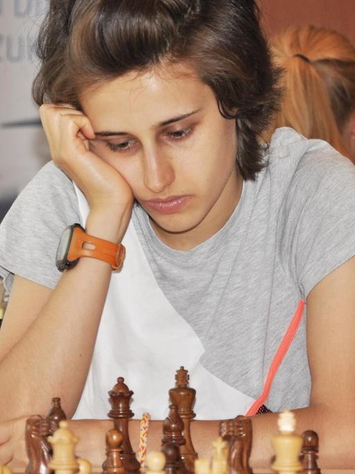 Die junge Schachspielerin Filiz Osmanodja schaut nachdenklich auf ein Schachbrett.