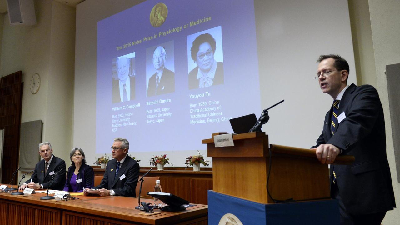 Urban Lendahl (r) verkündet bei der Pressekonferenz am 5. Okotober 2015 die Gewinner des Medizin-Nobelpreises: William Campbell, Satoshi Omura und Youyou Tu (Porträts von links nach rechts).