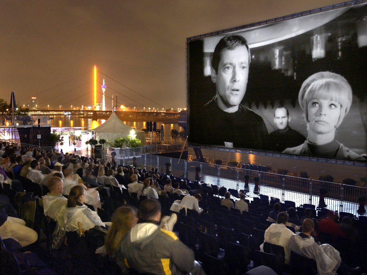 In einem Open-Air-Kino wird ein Film aus der Science-Fiction-Serie "Raumpatrouille – Die phantastischen Abenteuer des Raumschiffes Orion" gezeigt. In einem Open-Air-Kino wird ein Film aus der Science-Fiction-Serie "Raumpatrouille – Die phantastischen Abenteuer des Raumschiffes Orion" gezeigt.