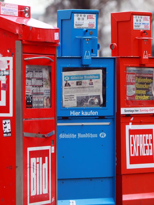 Blick auf vier Zeitungsautomaten.
