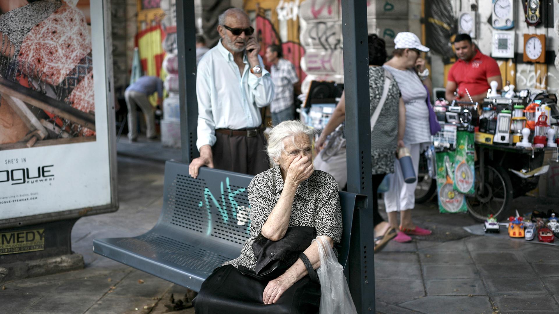 Eine Seniorin wartet an einer Bushaltestelle in Athen. Eine Seniorin wartet an einer Bushaltestelle in Athen.