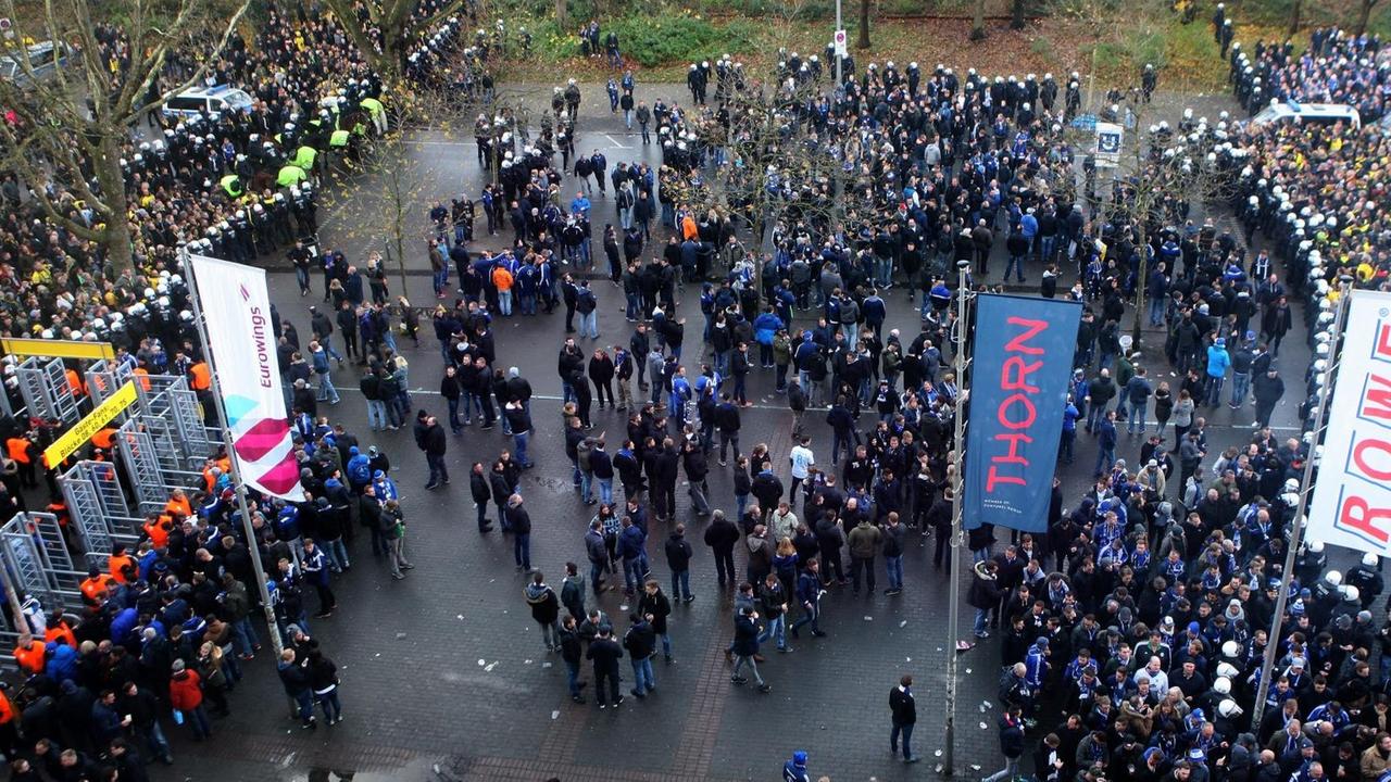 Schalkefans stehen durch Polizisten getrennt von den Dortmund-Fans vor dem Stadion. Luftaufnahme Schalkefans stehen durch Polizisten getrennt von den Dortmund-Fans vor dem Stadion. Luftaufnahme