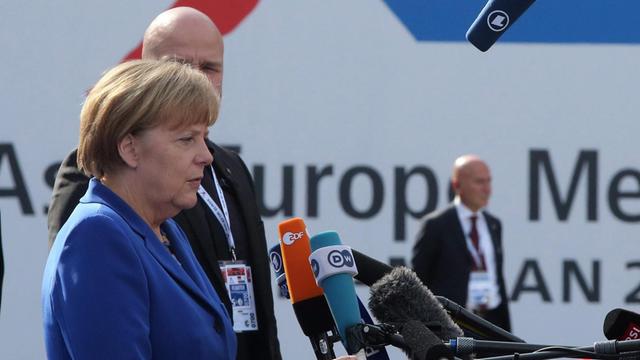 Angela Merkel spricht in eine Reihe von Fernseh- und Radiomikrofonen.