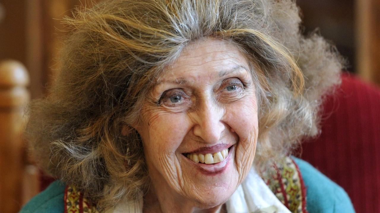 Eine ältere Frau mit langen Haaren lacht jemanden an. Eine ältere Frau mit langen Haaren lacht jemanden an.