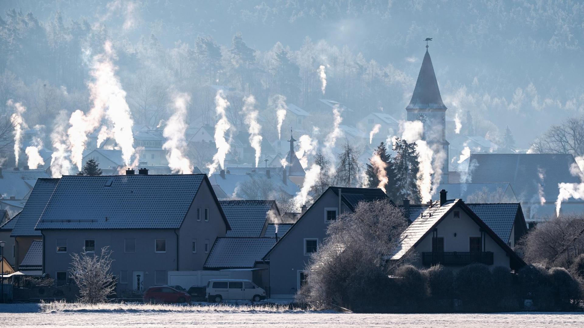 Die Schornsteine auf den Dächern der Häuser rauchen in der kalten Luft in Luthe-Wildenau. Die Schornsteine auf den Dächern der Häuser rauchen in der kalten Luft in Luthe-Wildenau.