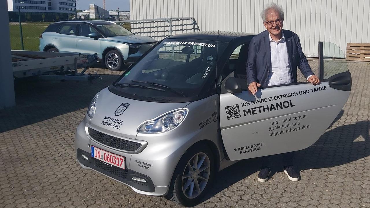 Ein Mann steht vor einem Auto mit einer Methanol-Brennstoffzelle. Ein Mann steht vor einem Auto mit einer Methanol-Brennstoffzelle.