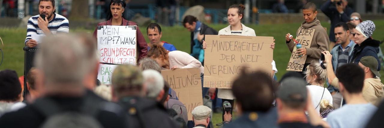 Bei einer Demonstration gegen Corona-Beschränkungen halten Demonstranten Plakate hoch andere schauen dabei zu. Bei einer Demonstration gegen Corona-Beschränkungen halten Demonstranten Plakate hoch andere schauen dabei zu.