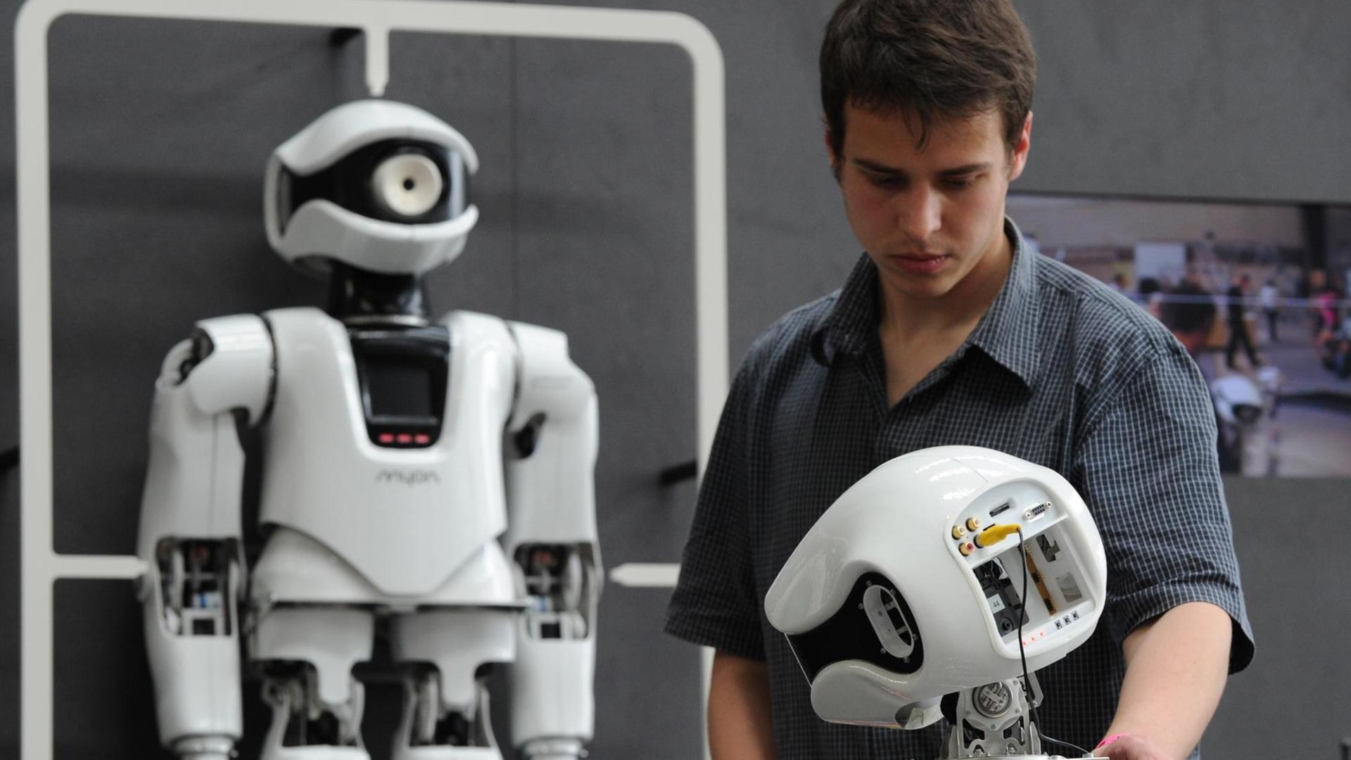 Christian Benkendorf von der Humboldt-Universität Berlin steht am Donnerstag (10.06.2010) auf dem Internationalen Design-Festival ((DMY) in Berlin neben dem Roboter "Myon". Christian Benkendorf von der Humboldt-Universität Berlin steht am Donnerstag (10.06.2010) auf dem Internationalen Design-Festival ((DMY) in Berlin neben dem Roboter "Myon".