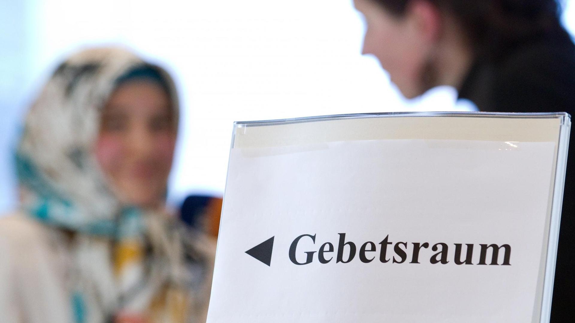 Eine Studentin in der Bibliothek der Universität Osnabrück bei der Auftaktveranstaltung für die Imamweiterbildung hinter einem Schild "Gebetsraum". Eine Studentin in der Bibliothek der Universität Osnabrück bei der Auftaktveranstaltung für die Imamweiterbildung hinter einem Schild "Gebetsraum".