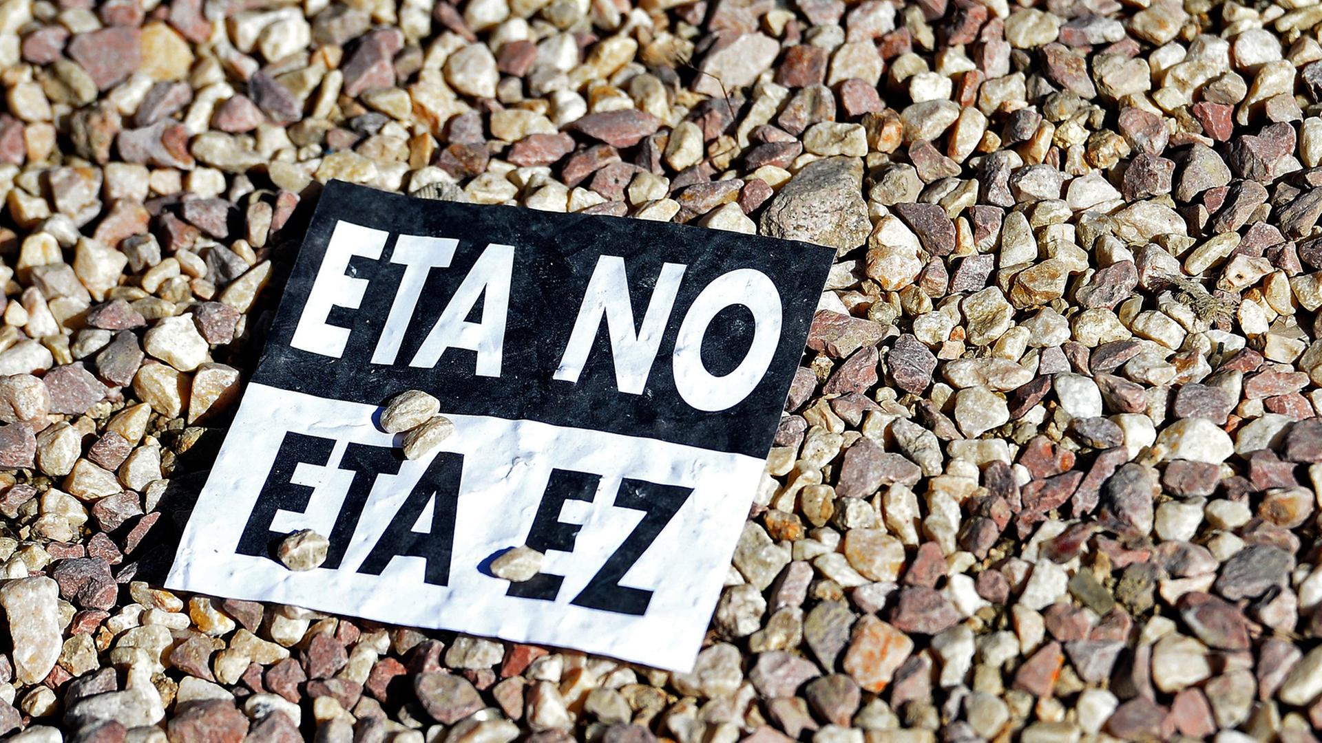 "ETA nein" auf Spanisch und auf Baskisch steht auf einem Aufkleber, der auf Kieselsteinen liegt