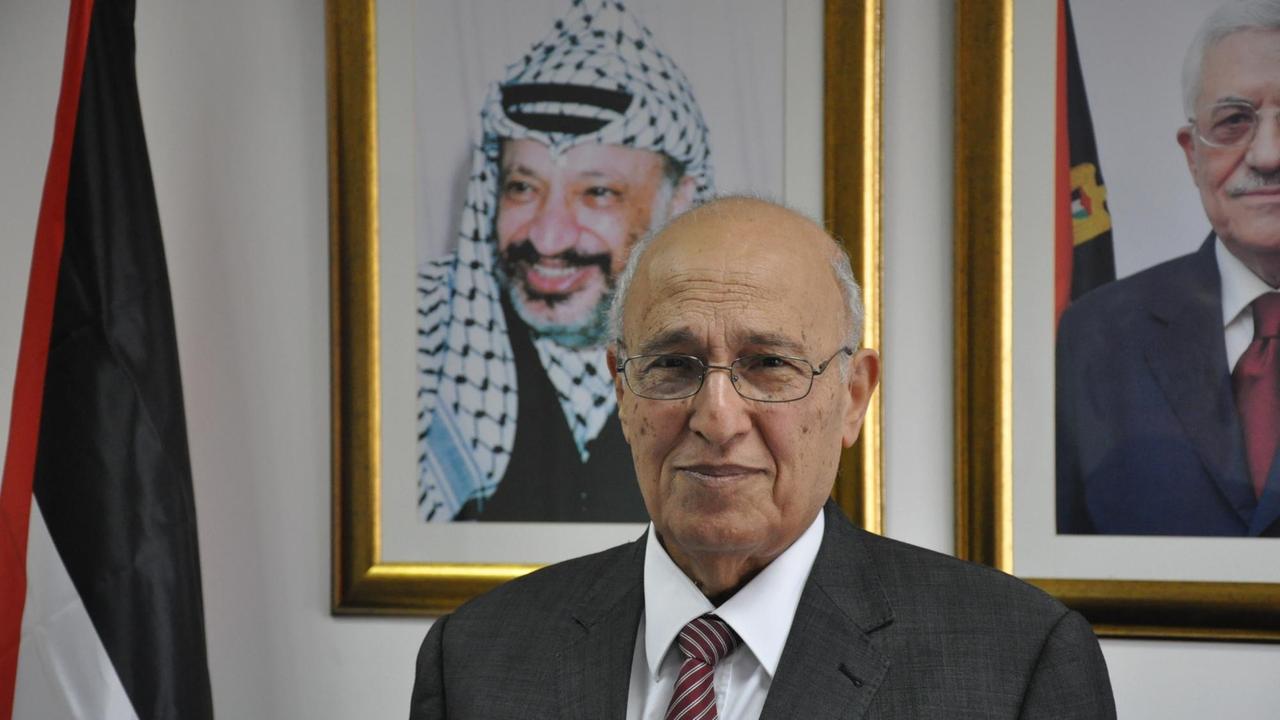 Nabil Schaath von der Palästinensischen Autonomiebehörde steht in seinem Büro. Hinter ihm ein Bild von Jasir Arafat.
