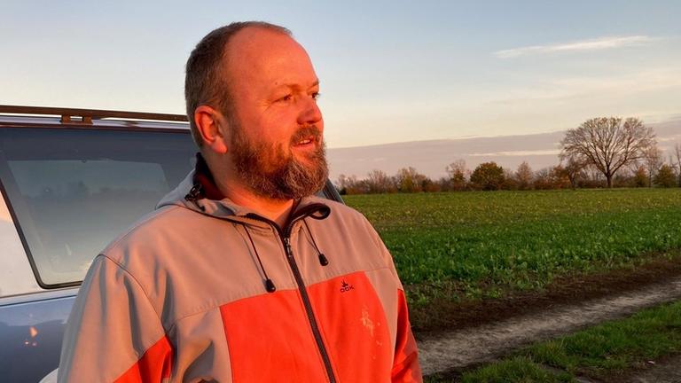 Landwirt Mark Dümichen steht neben seinem Auto auf dem Feld. Landwirt Mark Dümichen steht neben seinem Auto auf dem Feld.