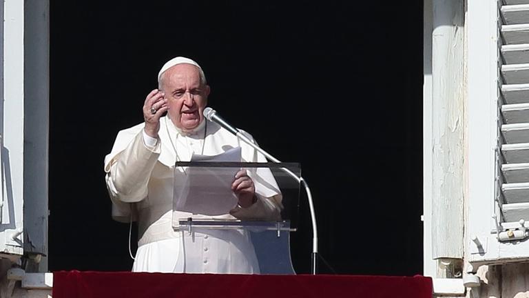 Papst Franziskus während des Angelus-Gebets auf dem Petersplatz. Er steht am offenen Fenster und hebt die rechte Hand. Papst Franziskus während des Angelus-Gebets auf dem Petersplatz. Er steht am offenen Fenster und hebt die rechte Hand.