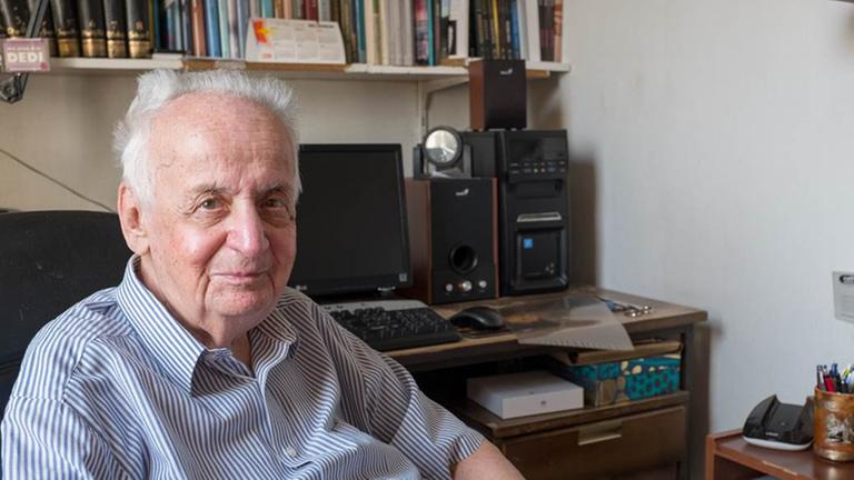 Ein älterer Mann sitzt in einem Arbeitsstuhl. Hinter ihm ist ein Computer und ein Bücherregel. Es ist Ivan Ivanji in seinem Arbeitszimmer in Belgrad. Ein älterer Mann sitzt in einem Arbeitsstuhl. Hinter ihm ist ein Computer und ein Bücherregel. Es ist Ivan Ivanji in seinem Arbeitszimmer in Belgrad.