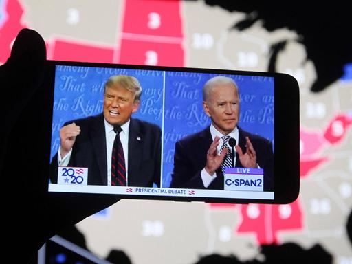 US-Präsident Donald Trump von den republikanern und sein Herausforderer, der frühere US-Vize-Präsident Joe Biden während der ersten TV-Debate auf einem Smartphone-Bildschirm. Im Hintergrund eine Karte der USA.