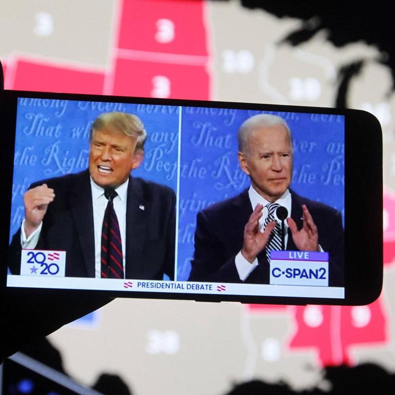US-Präsident Donald Trump von den republikanern und sein Herausforderer, der frühere US-Vize-Präsident Joe Biden während der ersten TV-Debate auf einem Smartphone-Bildschirm. Im Hintergrund eine Karte der USA.